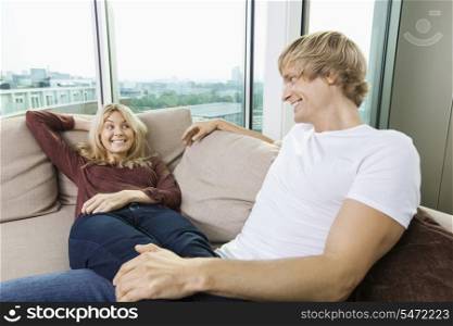 Relaxed couple looking at each other on sofa at home