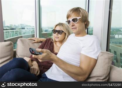 Relaxed couple wearing 3D glasses and watching TV at home