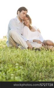 Relaxed couple with eyes closed sitting on grass in park