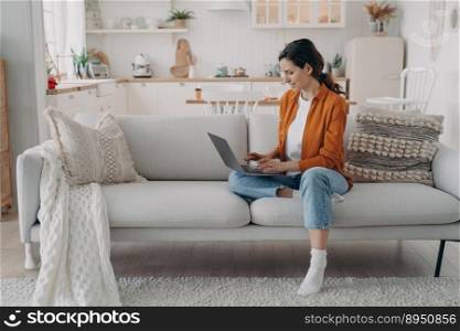 Relaxed european woman working with computer at home. Caucasian Lady is sitting on couch. Manager is consulting from home. Remote work in cosy living room, kitchen interior.. Relaxed european woman working with computer at home. Manager is consulting. Remote work.