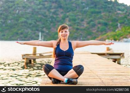 relaxed girl on a pier in the lotus position