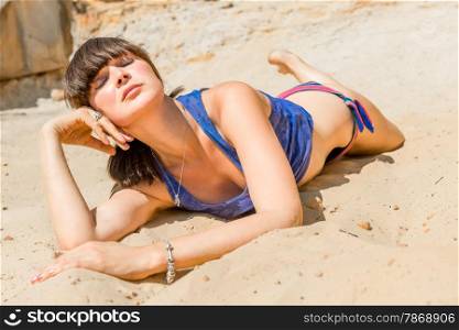 relaxed girl on a sandy beach for sunbathing with eyes closed