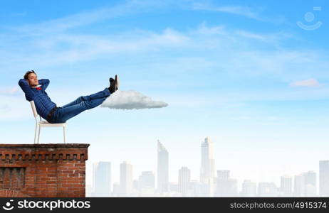 Relaxed guy. Young man sitting in chair with legs up and relaxing