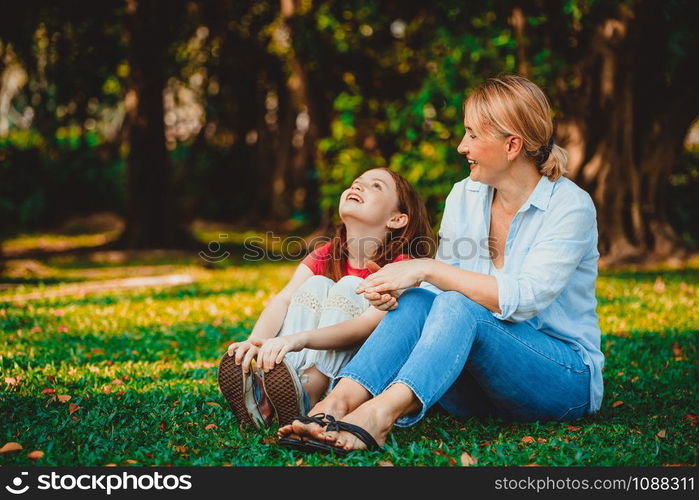 Relaxed happy mother and little kid daughter in outdoors public park. Parenthood and child concept.