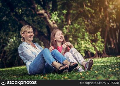 Relaxed happy mother and little kid daughter in outdoors public park. Parenthood and child concept.. Happy mother and little kid daughter in park.