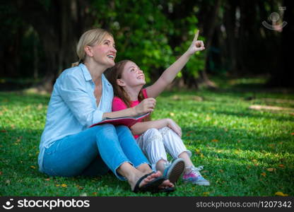 Relaxed happy mother and little kid daughter in outdoors public park. Parenthood and child concept.. Happy mother and little kid daughter in park.