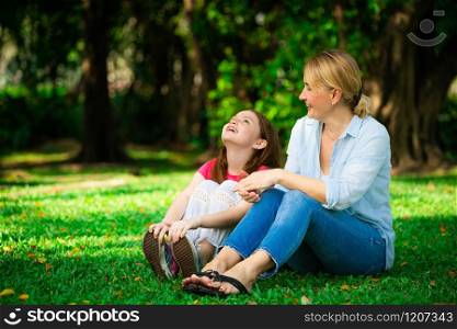 Relaxed happy mother and little kid daughter in outdoors public park. Parenthood and child concept.. Happy mother and little kid daughter in park.