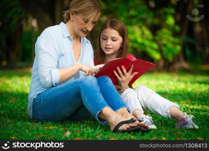 Relaxed happy mother and little kid daughter in outdoors public park. Parenthood and child concept.. Happy mother and little kid daughter in park.