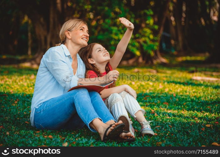 Relaxed happy mother and little kid daughter in outdoors public park. Parenthood and child concept.