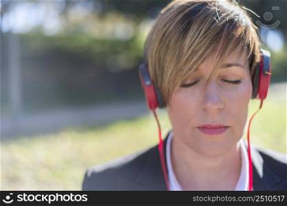 Relaxed lady listening to music and meditating outdoors in the nature