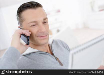 relaxed man holding notebook and talking on telephone
