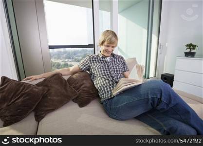 Relaxed mid-adult man reading book in living room at home