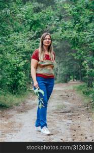 Relaxed middle aged woman walking at the forest