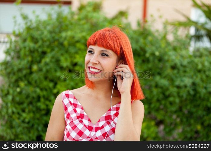 Relaxed red haired woman listening music in a park