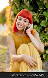 Relaxed red haired woman with a mobile in the park in a sunny day
