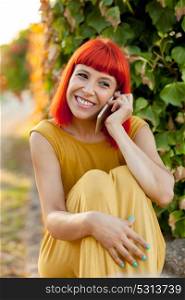 Relaxed red haired woman with a mobile in the park in a sunny day