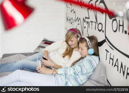 Relaxed sisters listening to music at home