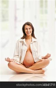 Relaxed, smiling and pregnant mother in white interior