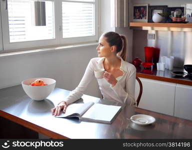 Relaxed woman drinking coffee in kitchen and looking out the window