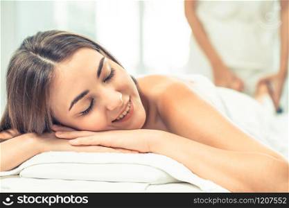 Relaxed woman getting back massage in luxury spa with professional massage therapist in background. Wellness, healing and relaxation concept.