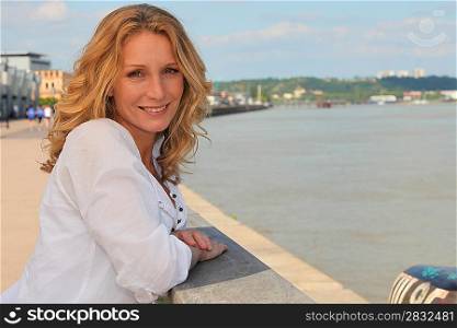 Relaxed woman leaning out over the Garonne river at Bordeaux, France