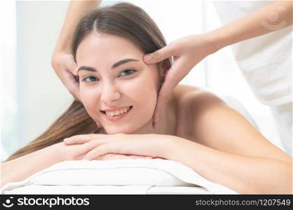 Relaxed woman lying on spa bed for facial and head massage spa treatment by massage therapist in a luxury spa resort. Wellness, stress relief and rejuvenation concept.. Woman gets facial and head massage in luxury spa.