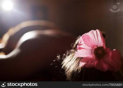 Relaxed woman with pink flower in hair lying at beauty spa salon and waiting for treatments. Woman at beauty spa prepared for procedure