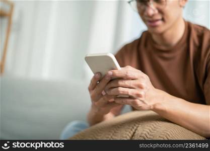 Relaxed young asian man using smart phone spending time checking news social media.