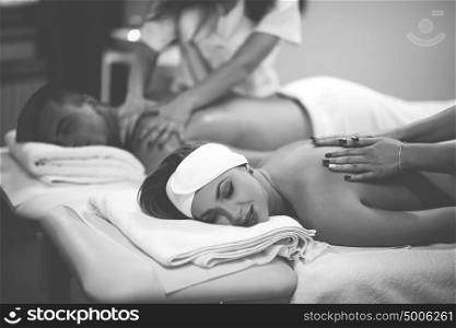 Relaxed young beautiful couple receiving a back massage from masseur in a spa
