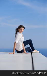 relaxed young beautiful woman in front of luxury modern home villa on balcony on sunny day