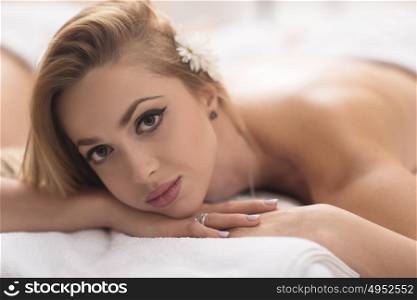 Relaxed young beautiful woman laying on massage table