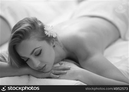 Relaxed young beautiful woman laying on massage table