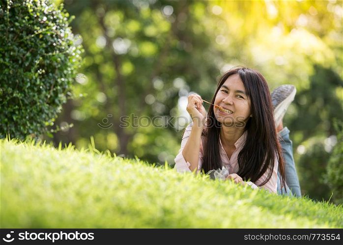 Relaxed Young Beautiful Woman With Smiling Face Enjoy Eating Pork Stick In The Park. Time To Relax After Work. Horizontal.Blurred Background.Film effect.