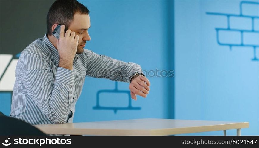 relaxed young businessman using smart phone at modern startup business office