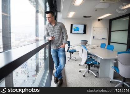 relaxed young businessman using smart phone at modern startup business office meeting room with big window and city in backgronud