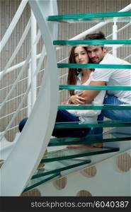 relaxed young couple on spiral glass stairs in modern home villa indoors