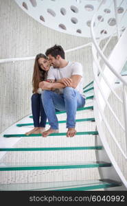 relaxed young couple on spiral glass stairs in modern home villa indoors