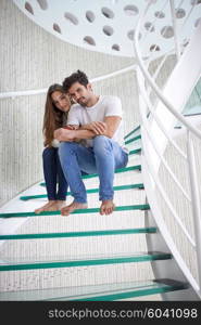 relaxed young couple on spiral glass stairs in modern home villa indoors