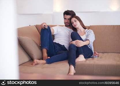 Relaxed young couple watching tv at home in bright living room