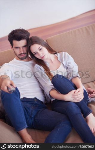 Relaxed young couple watching tv at home in bright living room