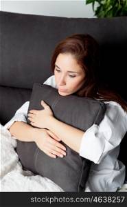Relaxed young girl hugging a cushion on the sofa at home