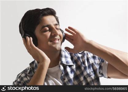 Relaxed young guy listening music over colored background