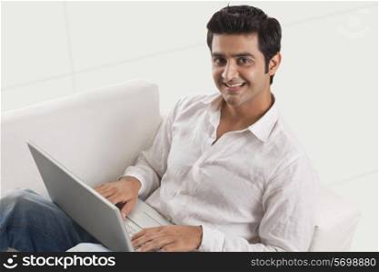 Relaxed young man on sofa using laptop