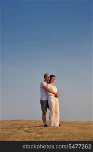 relaxed young pasionate couple enjoying the sunset beauty on their honeymoon, on a desert with orange background