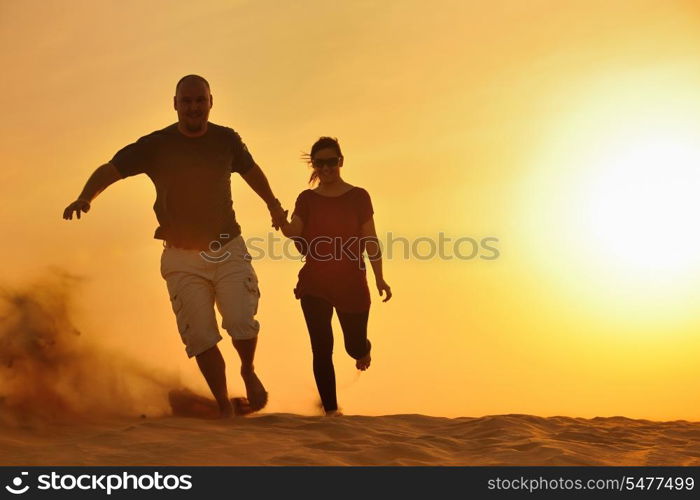 relaxed young pasionate couple enjoying the sunset beauty on their honeymoon, on a desert with orange background