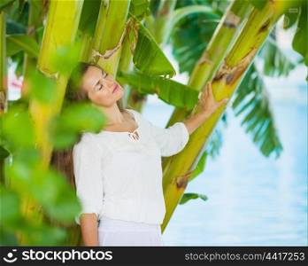 Relaxed young woman among tropical palms