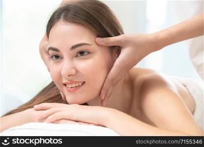 Relaxed young woman at the luxury wellness spa.. Woman gets facial and head massage in luxury spa.