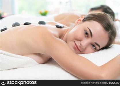 Relaxed young woman at the luxury wellness spa.. Hot stone massage treatment by therapist in spa.