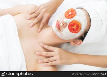 Relaxed young woman at the luxury wellness spa.. Woman get facial mask with tomato cream extract.