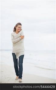 Relaxed young woman in sweater walking on lonely beach